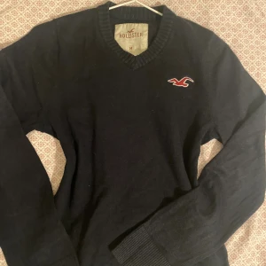 Mörkblå v-ringad tröja Hollister - Mörkblå v-ringad tröja från Hollister med broderad logga på bröstet. Perfekt för dig som gillar en klassisk och höstig look🍁 Bra skick och är i storlek M.  Skriv för fler frågor osv.