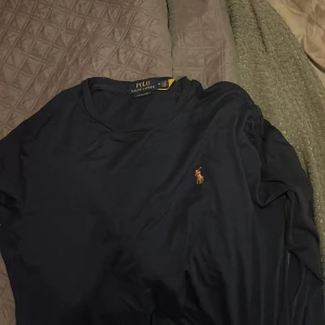 Mörkblå långärmad tröja Polo Ralph Lauren - Säljer en stilren mörkblå långärmad tröja från Polo Ralph Lauren med klassisk broderad logga på bröstet. Perfekt för dig som gillar enkel och tidlös design. Skön passform och mjukt material.