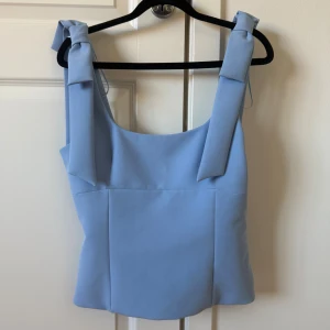 Blå topp från Zara - Supersöt ljusblå topp från Zara med rosetter. Storlek M men passar mig som har S. Använd fåtalgånger.