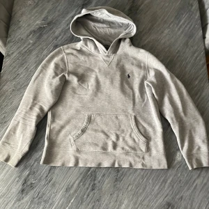 Grå  Polo Ralph Lauren hoodie - Snygg grå hoodie från Polo Ralph Lauren med klassisk broderad logga på bröstet. Tröjan har huva, magficka och långa ärmar. 