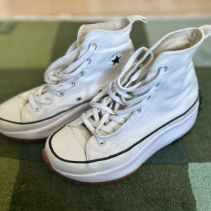 Vita Converse Run Star Hike sneakers - Säljer ett par vita Converse Run Star Hike sneakers med högt skaft, snörning och chunky plattformssula i gummi. Skorna har den klassiska Converse-loggan på sidan och en stjärndetalj på hälen. Ovandelen är i canvas och sulan har kontrastfärger i brunt och svart.