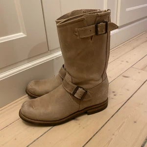 Beige Primeboots i skinn med dragkedja - Snygga beige Primeboots i äkta skinn med robust design, rund tå och dekorativa spännen. Guldiga dragkedjor baktill gör dem lätta att ta på. Fint skick och varsamt använda då de tyvärr är försmå för mig!
