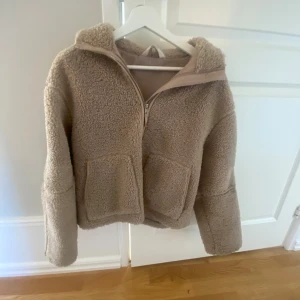 Beige teddyjacka med dragkedja - Mysig beige teddyjacka med två stora fickor framtill och halv dragkedja. Priset går att diskutera 