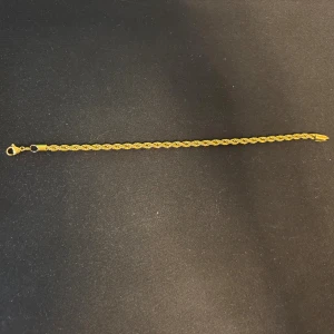 Guldigt kordell armband - Snyggt armband i guldton med tvinnad kedja och klassisk karbinlås. Perfekt för dig som gillar stilrena och eleganta accessoarer. Passar lika bra till jeans som till mer dressade outfits. Enkel att matcha med andra smycken.