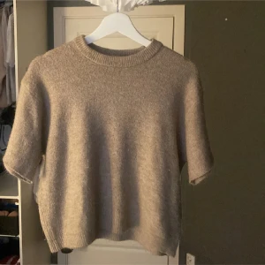 Beige stickad kortärmad tröja - Jättefin beige stickad tröja med avklippta ärmar, går att tvätta utan att de blir fult. 