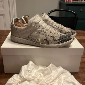 Maison Margiela skor - Maison Margiela skor med svart färg. Dom har slitna detaljer som var där men har fått några hål och ett större, (syns inte lika mycket när man har på dom) Boxen är med. Dom är 41 1/2 och passar från 41-42