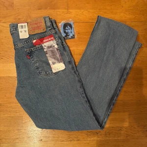 Levi's 505 blå jeans regular fit - Helt nya med tags klassiska Levi's 505 jeans i blå denim med regular fit och rak passform. Byxorna har fem fickor, gylf med dragkedja och ikonisk röd Levi's-tagg på bakfickan. Perfekt för dig som gillar tidlös stil och vill ha ett par jeans som funkar till allt.