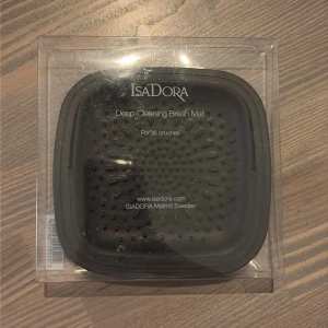 IsaDora Deep-Cleaning Brush Mat - Jag säljer en helt ny och oöppnad IsaDora Deep-Cleaning Brush Mat – ett smart tillbehör för rengöring av sminkborstar. Med denna silikonmatta rengör du borstarna snabbt och hygieniskt – perfekt för dig som vill hålla din makeup-rutin fräsch och borstarna i toppskick.