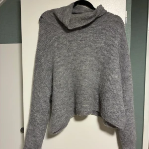 Grå stickad tröja från Bik Bok XL - Mysig grå stickad tröja från Bik Bok i alpackablandning. Tröjan har en lös och oversized passform med lång ärm och hög krage. Perfekt för kyliga dagar och enkel att styla till jeans eller kjol. Använd men är i fint skick 💕