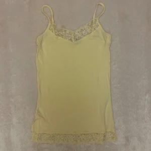 Gul linnetopp med spetsdetaljer - Supersöt ljusgul linnetopp med smala axelband och dekorativ spets både vid halsringningen och längst ner. Skriv vid fler frågor. 💓💓  
