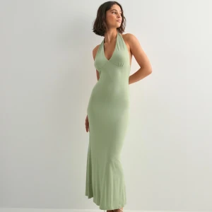 Ljusgrön långklänning med halterneck - Säljer en stilren ljusgrön långklänning med halterneck och v-ringad front. Klänningen har en figurnära passform och är ärmlös, vilket ger en snygg och modern siluett. Perfekt för dig som gillar minimalistisk design och mjuka material.
