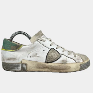 PHILIPPE MODEL PSRX - Säljer ett par vita Philippe Model sneakers med gröna detaljer och platt sula. Skorna har snörning och är tillverkade i skinn och syntet. Perfekta för dig som gillar stilrena och klassiska sneakers. Strl 41 på skorna. Bara skorna som ingår. 