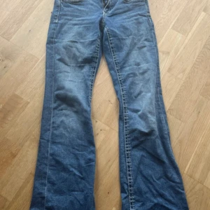 Blå bootcut jeans från Gina Tricot - Snygga blå jeans från Gina Tricot i storlek 158. Modellen har klassisk bootcut med utsvängda ben och fem fickor. Jeansen är tillverkade i mjukt denimtyg och har normal passform med knapp och dragkedja framtill.