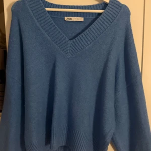 Blå stickad tröja med v-ringning Zara - Blå stickad tröja från Zara med bred v-ringning och ribbade detaljer vid hals och nederkant. Använd bara en gång. Supermjuk och skön att bära under kyliga dagar.💕