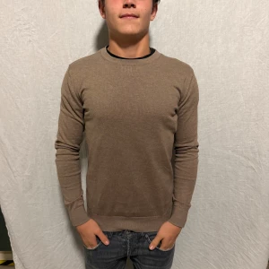 Brun Crew Neck från Dressman - Säljer en stilren brun tröja från Dressmann i Supima-bomull. Tröjan har rund halsringning, långa ärmar och ribbade muddar vid ärmslut och nederkant. Enkel och clean design som passar perfekt till jeans eller chinos.