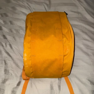 Gul ryggsäck från DB med fack - Snygg och praktisk ryggsäck från DB i stark gul färg. Väskan har en rektangulär form, justerbara axelremmar och flera smarta innerfack för laptop och småprylar. Materialet är slitstark polyester och insidan är fodrad i svart. Perfekt för skola eller äventyr. Lät ai göra en beskrivning men det är en DB ryggsäck den är knappt använd tror inte just denna säljs längre bara skriv om det finns någon fråga💕