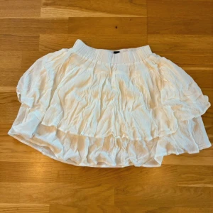 Vit volangkjol från Dazy - Supersöt vit kortkjol från Dazy (ASOS) med volanger och resår i midjan. Kjolen har ett luftigt och krusat tyg som ger en skön och flowy känsla. Perfekt för dig som gillar en feminin och trendig look med extra volym. Står storlek M, men passar S också!