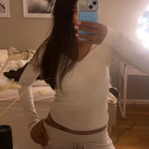 Vit långärmad topp med v-ringning - Säljer en stilren vit långärmad topp med v-ringad hals. Modellen är figurnära och har en enkel, clean look som passar perfekt till jeans eller mjukisbyxor. Mjuk och stretchig i materialet för en bekväm känsla.