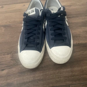 Converse One Star sneakers marinblå - Snygga Converse One Star sneakers i marinblå mocka med vit stjärndetalj på sidan och vit sula. Klassisk låg modell med mörkblåa snören och rund tå. 