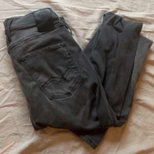 Replay grå jeansbyxor slim fit - Säljer ett par grå jeansbyxor från Replay i modellen slim fit. Byxorna är tillverkade i ganska mjukt material. Slitning/hål på vänster knä men utöver det väldigt bra skick. Hör av er vid frågor, hjälper alltid✌️