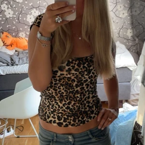 Leopardmönstrad topp med kort ärm - Säljer en snygg leopardmönstrad topp med korta ärmar och rundad halsringning. Toppen är figurnära och har en beige bas med svarta och bruna leopardfläckar. Endast använt 2 gånger! 