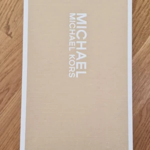 Michael Kors Alice Ballet ballerina - Snygga ballerina från Michael Kors i modellen Alice Ballet. Skorna är i brunt och svart skinn med quiltad svart innersula och guldfärgad detalj framtill. Perfekta för dig som vill ha en klassisk och stilren look med en touch av lyx.