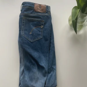 Blå jeans från Dondup, storlek 30 - Snygga blå jeans från Dondup i klassisk femficksmodell. Jeansen har en rak passform och är tillverkade i en mjuk bomullsblandning med lite stretch. Fina kontrastsömmar och läderpatch med logga bak i midjan. Made in Italy skriv om du har funderingar.