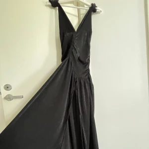 Elegant  Halterneck Långklänning – Elegant & Flowy! - Snygg långklänning i glansigt material med djup V-ringning, knytbara axelband och draperad midja!  oanvänd i utmärkt skick.                                                    Flera bilder skickas vid behov !