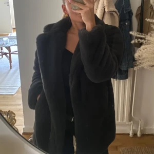 Marinblå pälsjacka från Zara - Säljer en svart pälsjacka med bred krage och lång ärm. Jackan har en oversized och mysig look, perfekt för kalla dagar. Den är tillverkad i mjukt fuskpälsmaterial och har en stilren, enkel design utan synliga knappar eller dragkedja.