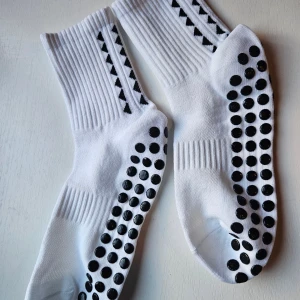 Vita greppstrumpor 49 kr par, 3-pack 129 kr - Vita sportstrumpor med svarta prickar under foten för extra grepp. Strumporna är ribbade vid skaftet och tillverkade i mjuk bomullsmix som andas. Perfekta för fotboll eller träning när du vill ha stabilitet och stil. Köp i par eller 3-pack. 