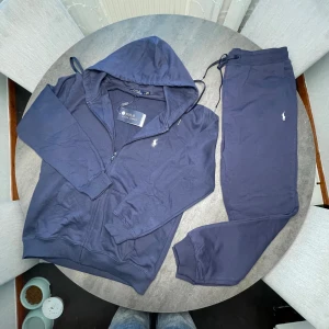 Marinblått set från Polo Ralph Lauren - Köpte fel storlek‼️Marinblå hoodie och byxor från Polo Ralph Lauren med dragkedja, huva och snörning. Klassisk broderad logga på bröstet och mjukt bomullsmaterial. Perfekt för chill dagar och snygg att matcha med jeans eller joggers.