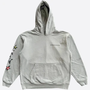Chrome Heart hoodie - Grå hoodie med stor stjärngrafik och tecknad figur på ryggen, samt tryck på ärmarna och bröstet. Feta detaljer med Sugguest-logga och coola motiv. Klassisk känguruficka och huva. Perfekt för dig som gillar streetwear och unika prints.