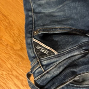 Replay skinny jeans blå, stl 26 - Säljer ett par blå skinny jeans från Replay i storlek 26. Jeansen har klassisk femficksdesign, snygga slitningar och kontrastsömmar. Modellen är tight och sitter snyggt längs benen. Perfekta för dig som gillar en smal siluett och vill ha ett par jeans med cool tvätt.