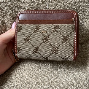 Brun och beige plånbok från MNG - Köpt för 450 Ish.Snygg plånbok från Mango i beige och brunt med rutigt mönster och bruna skinnkanter. Plånboken har dragkedja runtom och flera fack för kort och sedlar. Perfekt storlek för att ha med sig överallt däremot har den lite skador men ändå fin🥰