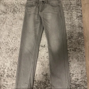 Gråa raka jeans från Indicode Jeans - Snygga grå jeans från Indicode Jeans i rak passform. Klassisk femficksmodell med knapp och dragkedja i gylfen. Jeansen har en stilren look och är tillverkade i mjukt jeanstyg som passar perfekt till en avslappnad stil.