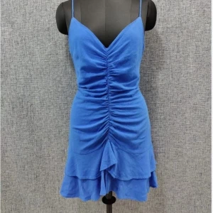 Blå omlottklänning från Zara - Supersöt blå kortklänning från Zara med smala axelband, v-ringning och snygg rynkdetalj framtill. Klänningen har volangkant nertill och öppen rygg med knyt. Perfekt för sommarens alla tillfällen!