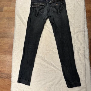 Miss Sixty gråa jeans 29 - Snygga gråa jeans från Miss Sixty med coola detaljer som silvriga nitar, dekorativa sömmar och unika fickor. Jeansen har låg midja och dragkedja framtill. Perfekta för dig som gillar en tight passform och streetig look. Har tecken på användning och ser vintage ut. Se bilder. Inga fläckar eller hål.