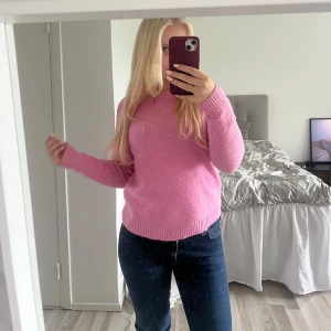 Rosa stickad tröja  - Supermysig rosa stickad tröja med rund hals och ribbade muddar. Perfekt för dig som vill ha en enkel men ändå färgglad look. Långärmad och i en normal passform som är lätt att styla med jeans eller kjol.