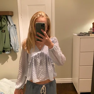 Ljusblå volangblus från Gina Tricot - Supersöt ljusblå blus från Gina Tricot med volangdetaljer och små prickar i tyget. Blusen har v-ringning, långa ärmar och en flowy passform. Perfekt för dig som gillar romantisk och trendig stil. Skulle säga att den är lite större i storleken än vad det står. Jag är 162 och den passar mig bra. Skriv vid frågor ☺️