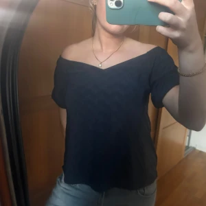 Svart offshoulder blus med broderi - Mörkblå  blus med offshoulder-modell och korta ärmar. Toppen har ett diskret broderat blommönster i tyget, storlek S 💙