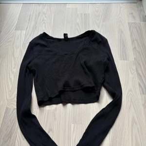 Svart croppad ribbad topp från SHEIN - Svart långärmad croppad topp från SHEIN. Toppen har v-ringning och är lite kortare. Toppen är i storlek XL men skulle säga att den är liten i storlek 