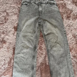 Gråa high waist jeans från Bershka - Säljer ett par gråa jeans från Bershka i modellen high waist straight. Jeansen har en snygg tvättad look, raka ben och klassiska fem fickor. Perfekta för dig som gillar en avslappnad men trendig stil.