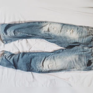G-Star Raw Denim ljusblå jeans 28/30 - Säljer ett par G-Star Raw Denim jeans i ljusblå tvätt med slitningar och distressed detaljer. Modellen har raka ben, stora bakfickor och klassisk femficksdesign. Jeansen är tillverkade i bomull och har en avslappnad, loose passform.