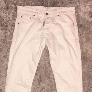 Vita jeans från Dsquared2, storlek 46 - Snygga vita jeans från Dsquared2 med klassisk femficksdesign och metallnitar. Byxorna har rak passform och är tillverkade i mjukt bomullsmaterial. Perfekt för dig som vill ha en clean och stilren look med exklusiv känsla.