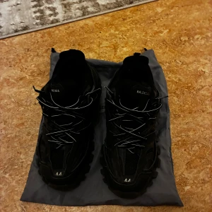  Track sneakers svarta - Säljer ett par svarta Track sneakers med chunky sula och coola detaljer. Skorna har mesh och syntetpaneler, reflekterande snören och -logga på plösen. Perfekta för dig som gillar streetstyle och vill sticka ut med en lyxig vibe.