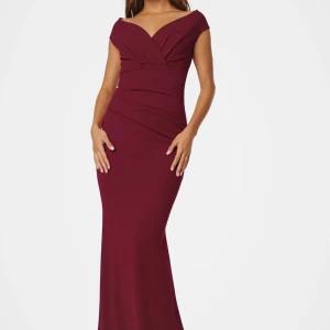 Vinröd balklänning - Säljer en elegant vinröd långklänning med omlott framtill och v-ringad offshoulder-överdel. Klänningen har figurnära passform och är tillverkad i ett mjukt, stretchigt material som ger en snygg siluett. Perfekt för bal eller festliga tillfällen. Endast använd vid ett tillfälle, väldigt fint skick!