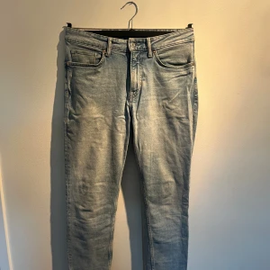 Ljusblå H&M jeans - Snygga ljusblå H&M jeans med klassisk femficksdesign och smal passform. Jeansen har en lätt tvättad look och raka ben, perfekt för dig som gillar en modern stil. Materialet är mjukt jeans och midjan är normal.