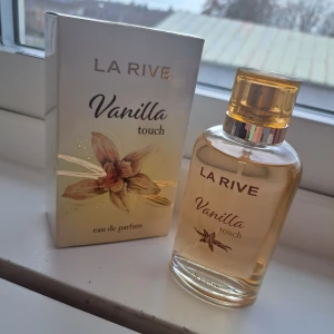 La Rive Vanilla Touch Parfym EDP 100 ml - La Rive Vanilla Touch eau de parfum med stilren design och vaniljtema. Perfekt för dig som vill ha en söt och mjuk vibe. Flaskan och förpackningen har en modern look som passar in i din samling.