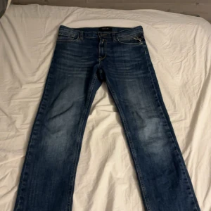 Replay blå jeans straight fit - Säljer ett par snygga blå jeans från Replay med klassisk straight fit. Jeansen har coola slitningar och kontrastsömmar, samt Replay-logga på bakfickan. Perfekt passform och tidlös stil, tillverkade i mjukt jeanstyg. Jeansen passar bäst om du är mellan 150-160cm lång.