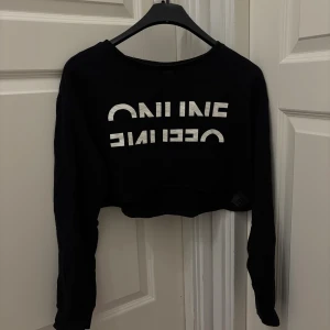 Svart croppad tröja från H&M Divided - Svart croppad långärmad tröja från H&M med vit text tryckt på framsidan. Tröjan har en loose passform och är tillverkad i mjuk bomull, använd ett fåtal gånger🌸☺️